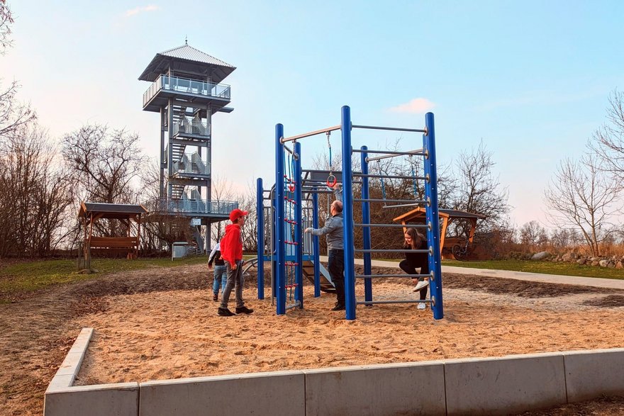 zeigt Aussichtsturm und Kinderspielgerät mit spielenden Personen